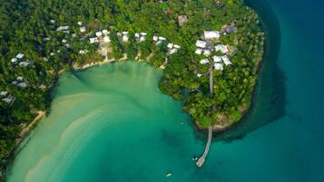 Overwater bungalows and villas nestle among lush greenery and palm trees, surrounded by a tranquil turquoise lagoon.
