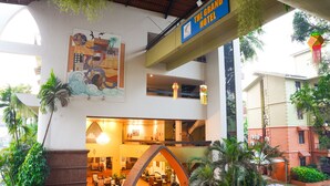 Un vestíbulo de hotel con un mural grande, varias zonas de estar y una escalera que conduce al piso superior.