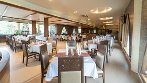 Un restaurante espacioso con numerosas mesas y sillas, dispuesto en un diseño amplio y corrido.