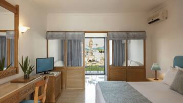 A hotel room with a bed, desk, chair, and a view of the outdoors.