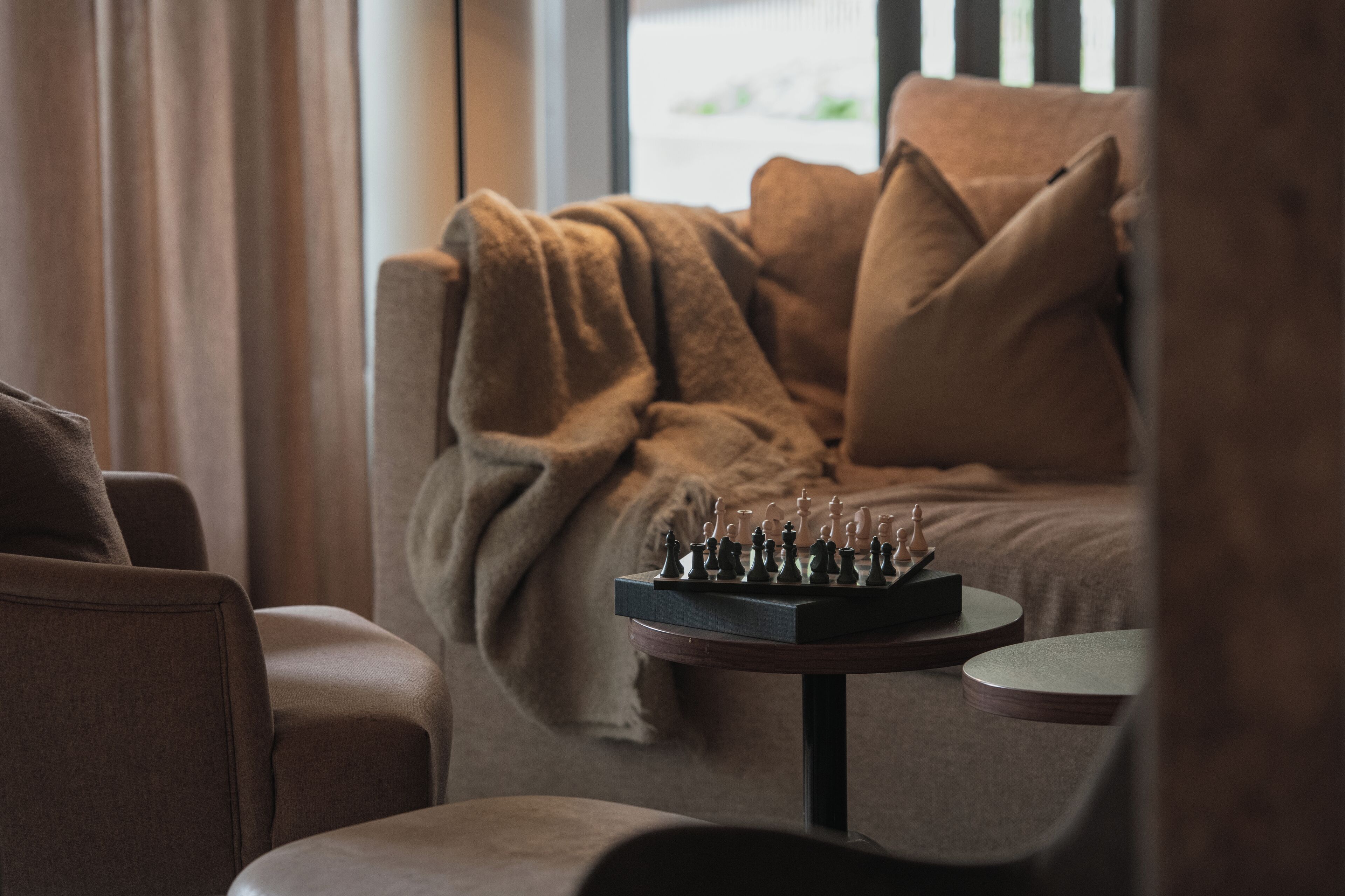 A cozy living area with a sofa and a small round table with a chessboard.