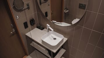 Un baño moderno con un lavamanos blanco, un espejo y un inodoro.