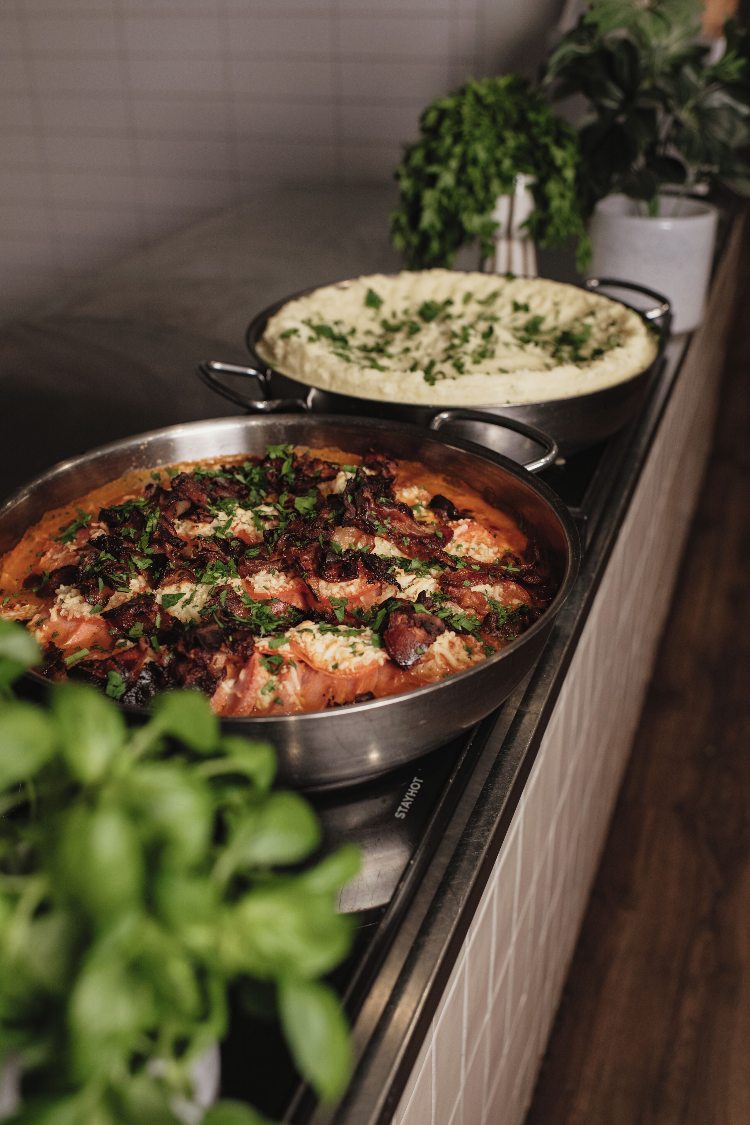 A kitchen counter with two dishes: one appears to be a baked dish topped with herbs and another looks like a creamy pasta dish.