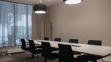 Una sala conferenze con un lungo tavolo, sei sedie e due lampadari a sospensione.
