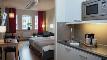 A hotel room with a bed, bedside table, lamp, and a view of buildings through the window.