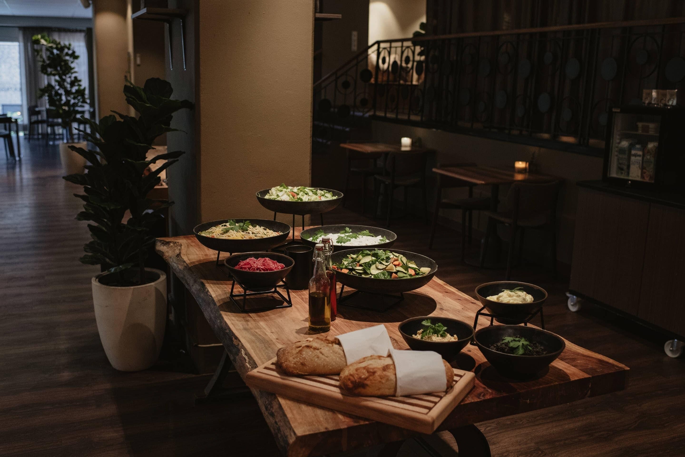 A dining area with a wooden table set with various dishes, a bottle of olive oil, and bread.