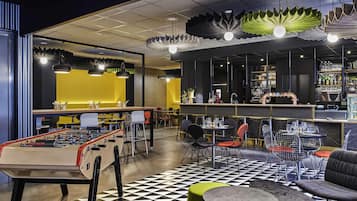 A modern bar area with a foosball table, seating, and a checkered floor.