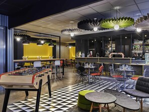 A modern bar area with a foosball table, seating, and a checkered floor.