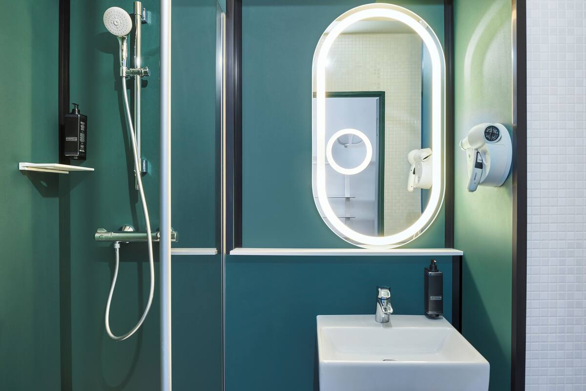 A modern bathroom with a shower, a sink, and a mirror with a lighted frame.