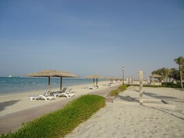 Uma praia com espreguiçadeiras, guarda-sóis e um céu claro.