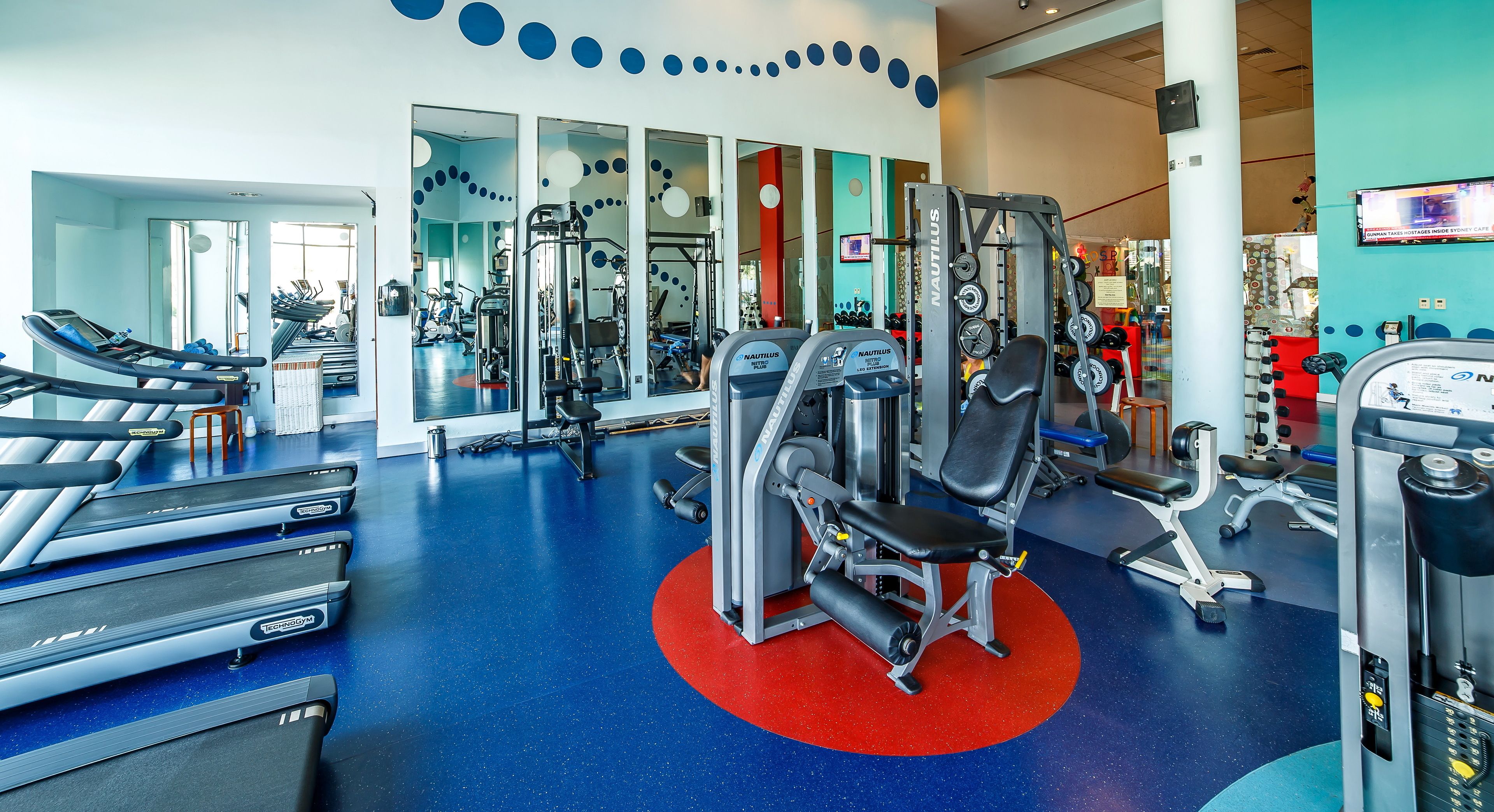 Une salle de sport équipée de tapis de course, d’appareils de musculation Nautilus et de poids libres.