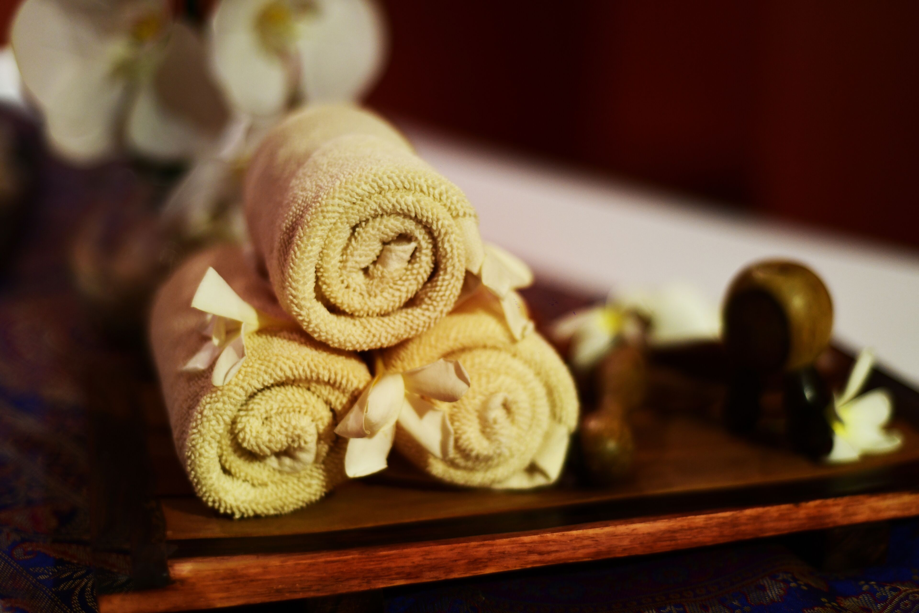 A wooden tray with rolled towels and a small bottle.