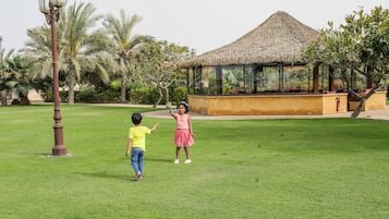 Relax in a serene tropical setting surrounded by lush greenery and a tranquil lawn.