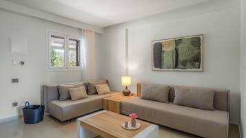 Una sala de estar moderna con dos sofás, una mesa de centro, una lámpara, un cuadro y una ventana con cortinas.