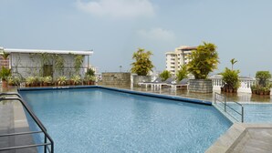 Piscina no terraço com espreguiçadeiras e plantas em vasos.