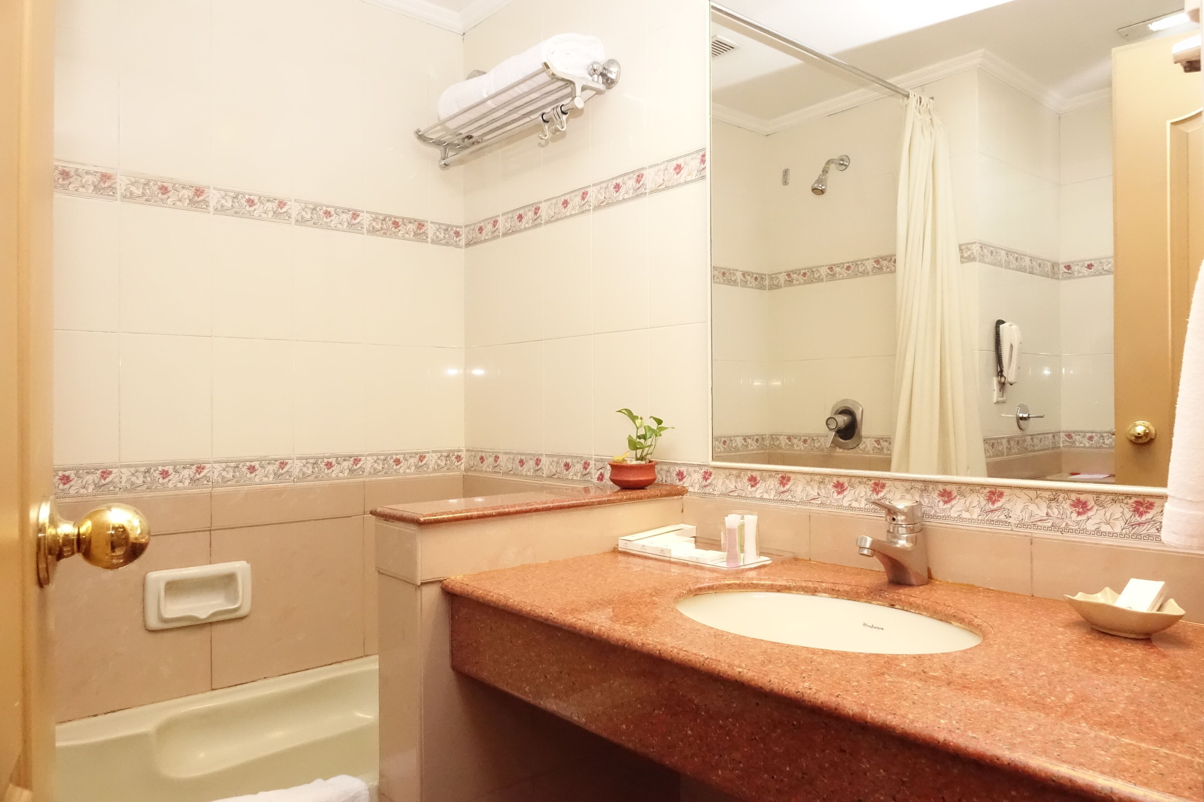 Un baño con lavamanos de mármol, bañera, perchero, espejo y cortina de ducha.