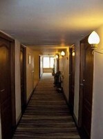 Un pasillo largo y estrecho con puertas de madera a ambos lados y suelo alfombrado.