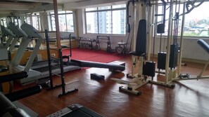 A gym with cardio machines, weightlifting equipment, and a red carpet.