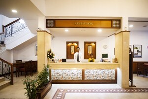 A reception area with a reception desk, a staircase, and a reception sign.