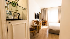 A hotel room with a bed, a desk with a chair, a television, and a dining table with chairs. - Liwan Hotel (Amman)