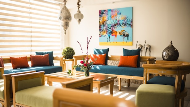 A well-lit living room with a sofa, chairs, a coffee table, and decorative items including a painting and a vase with flowers. - Liwan Hotel (Amman)