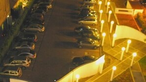 Un estacionamiento con coches y un edificio al fondo.
