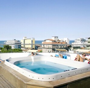 Una piscina sul tetto con idromassaggio circondata da poltrone relax, con vista sulla città costiera.