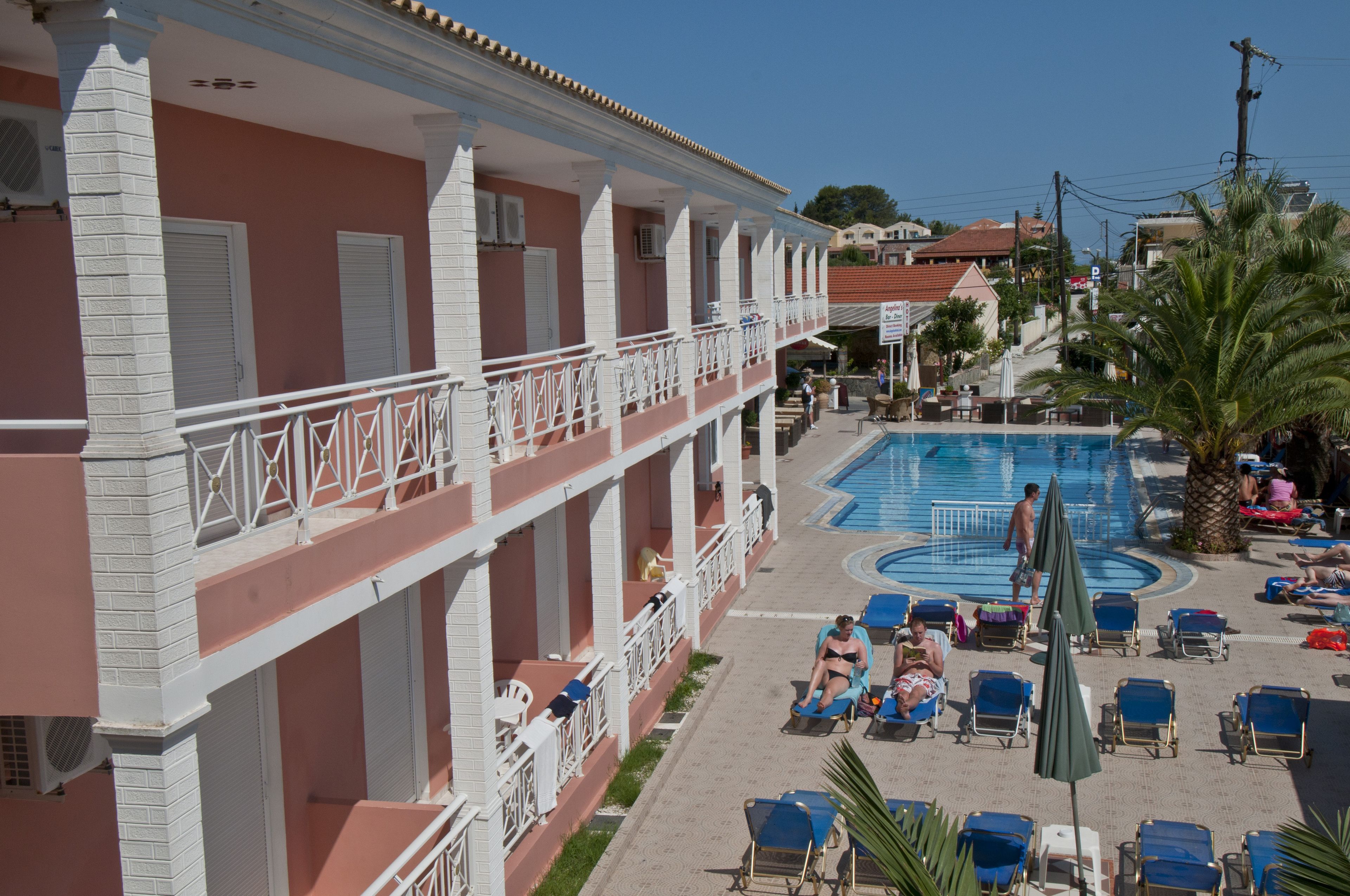Un hotel con zona de piscina, incluyendo sillas de descanso y sombrillas.