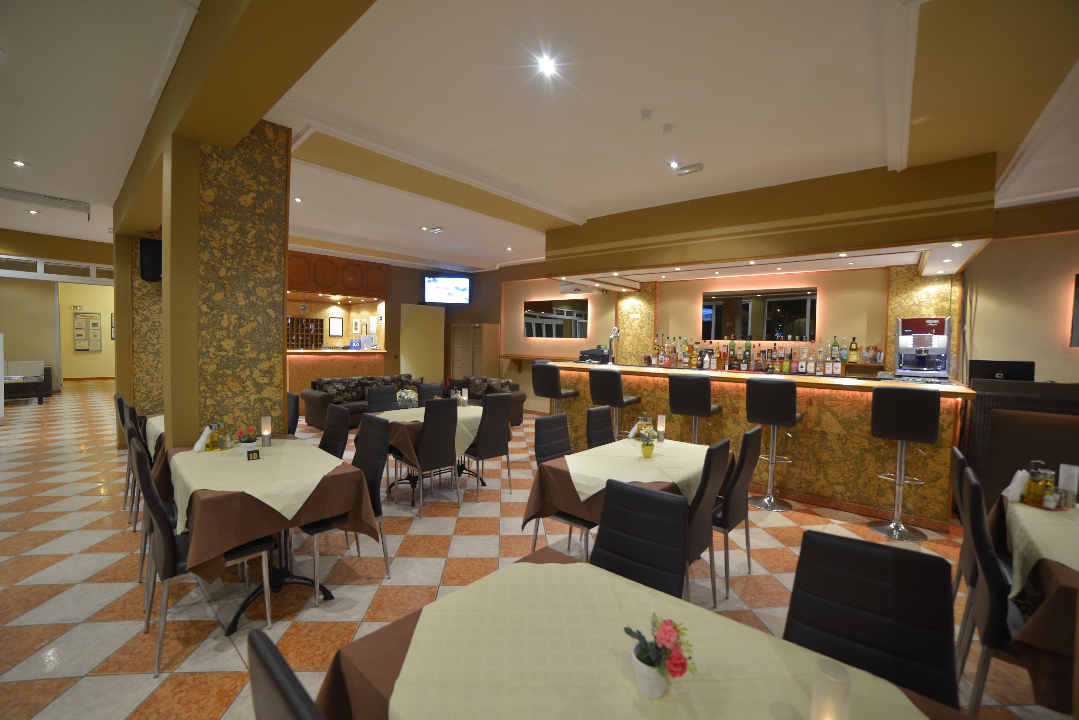 Un restaurant doté de nombreuses tables et chaises, d’un bar et d’un écran de télévision.