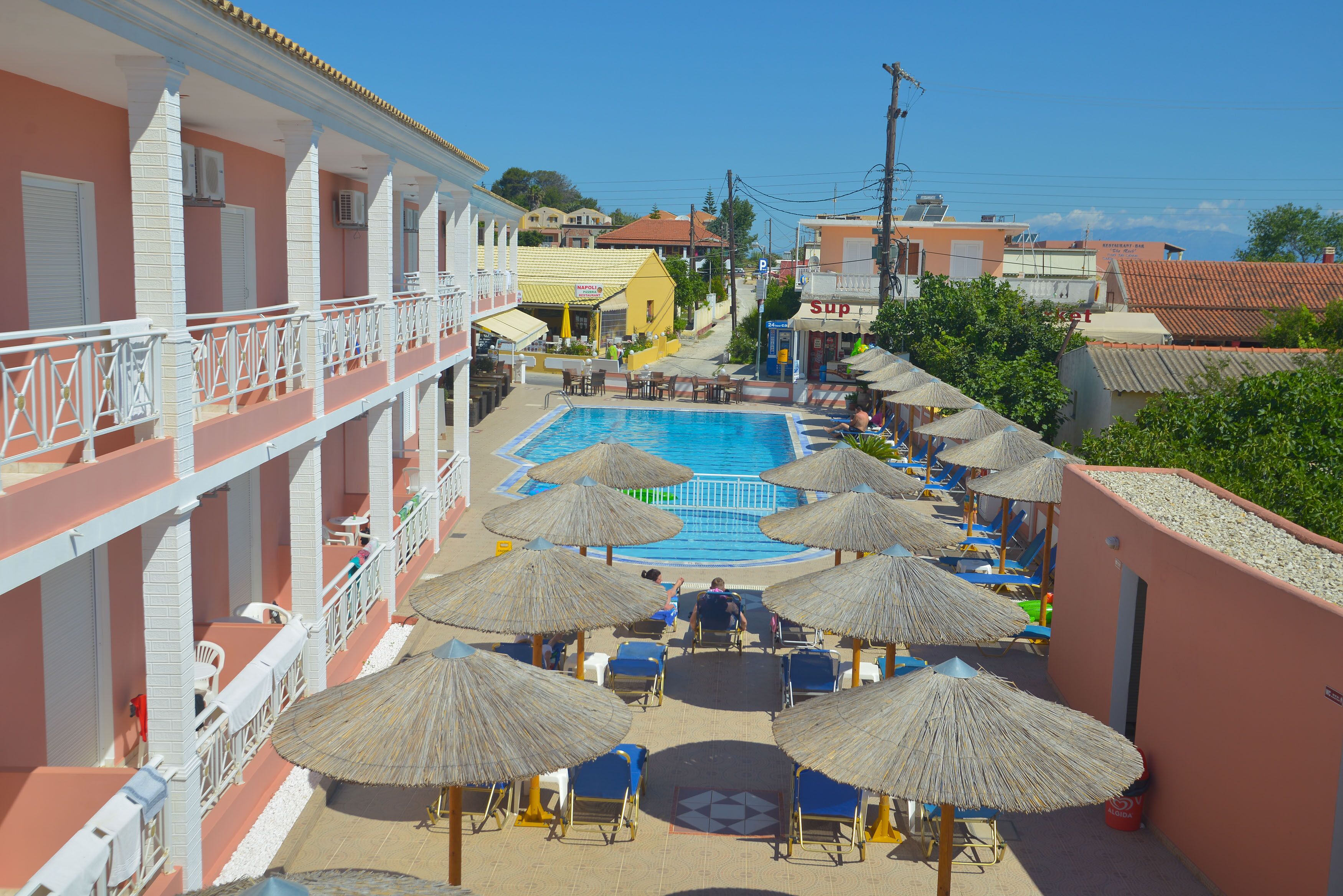 A hotel with a pool area, multiple lounge chairs, and umbrellas.