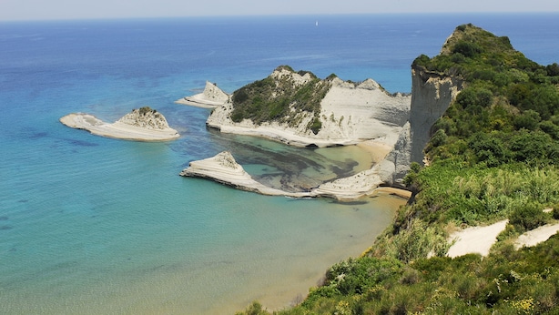 A coastal landscape with rocky formations and clear blue waters.