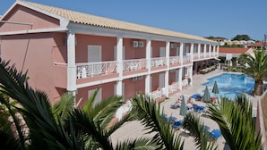 A hotel with a pool, outdoor seating, and palm trees.