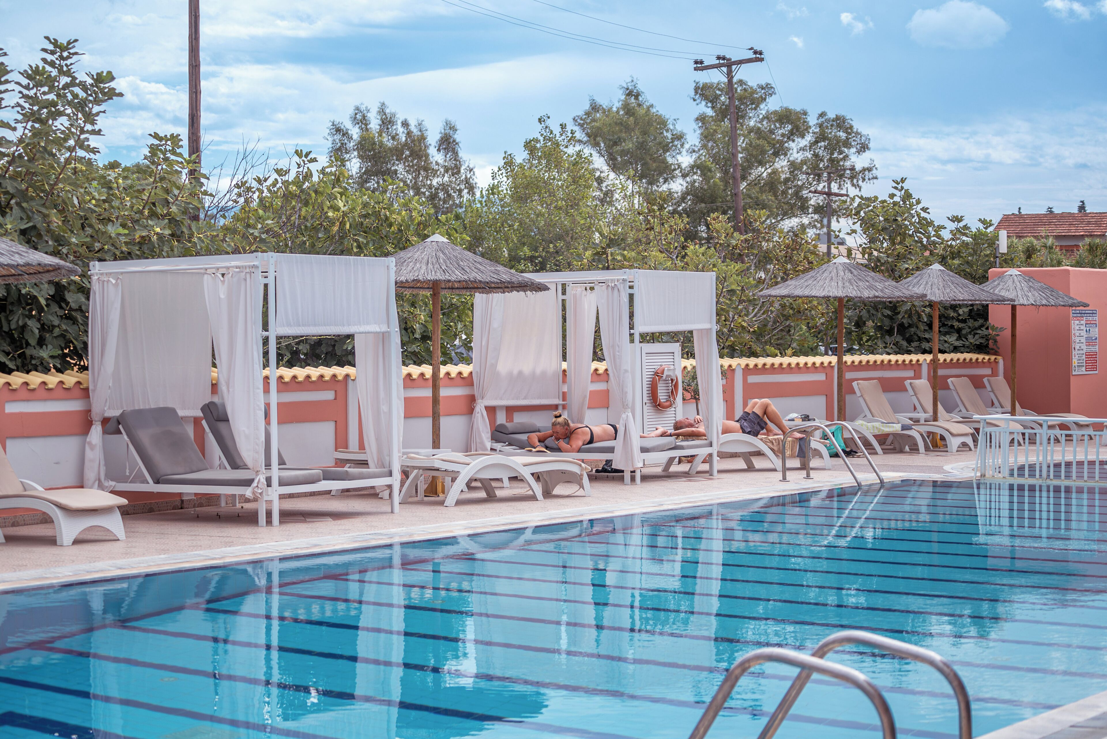Una piscina con sillas de descanso y toldos.