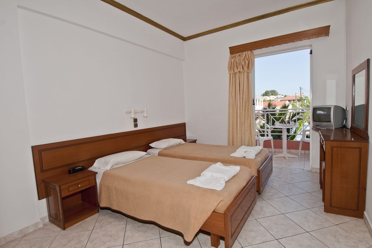 Een hotelkamer met twee bedden, een televisie, een bureau en een balkon met uitzicht.