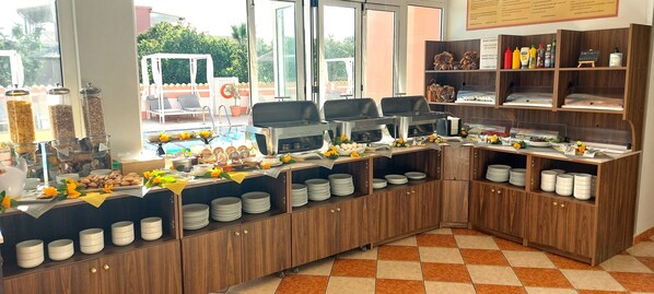 Montaje de bufé con varias estaciones de servicio, una variedad de alimentos y vistas al área exterior.
