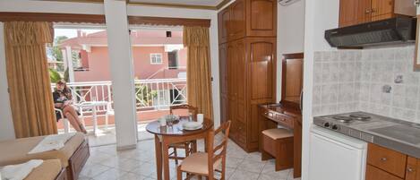 Una cocina compacta con gabinetes de madera, una estufa empotrada y un comedor con mesa y sillas.