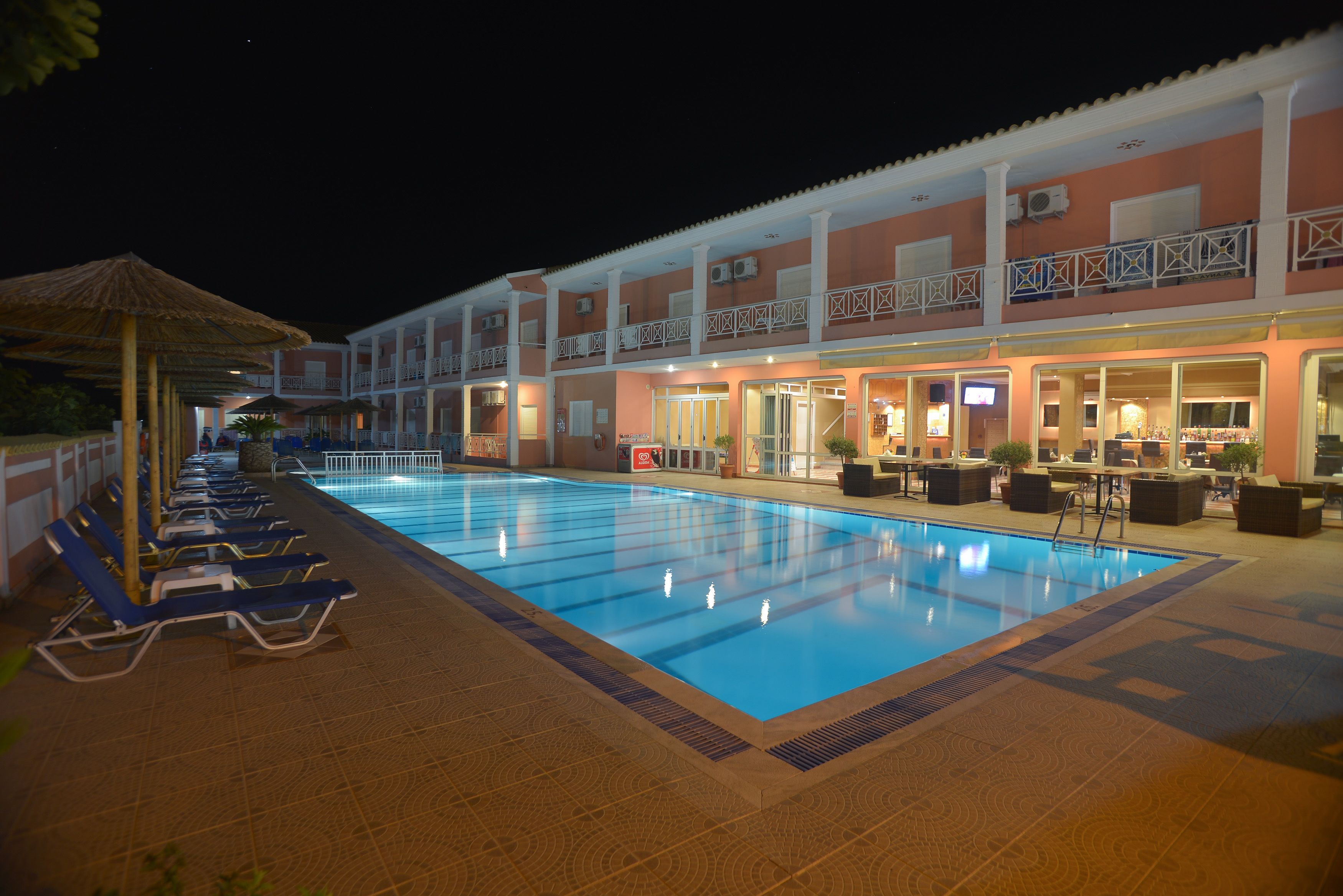 A swimming pool with lounge chairs and a building with balconies and outdoor seating.
