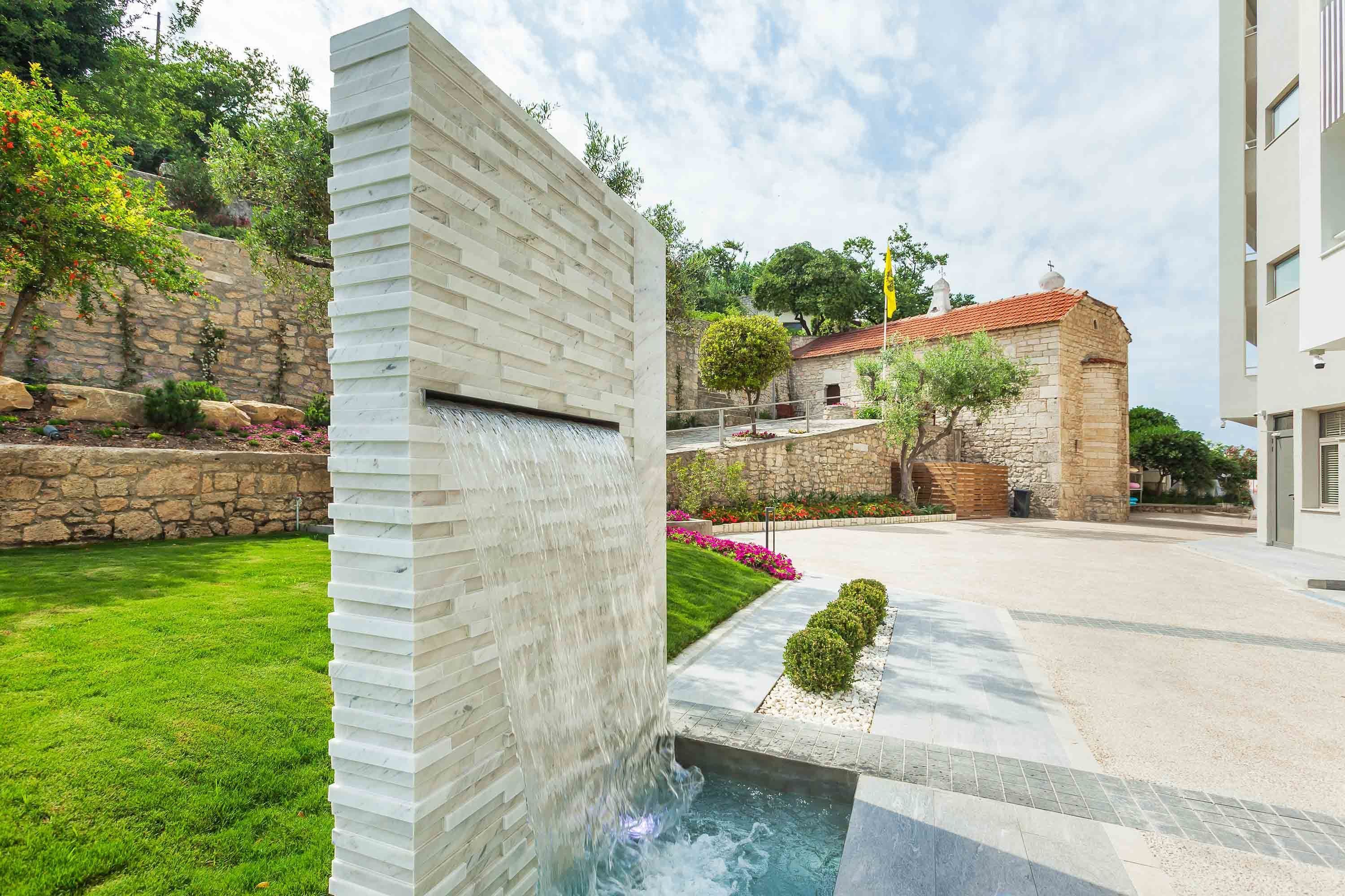 A courtyard with a water feature, stone walls, and a building with a red-tiled roof.