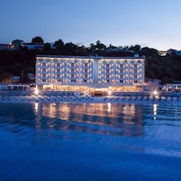 Un hotel de varios pisos con zona de piscina y vista a la playa.