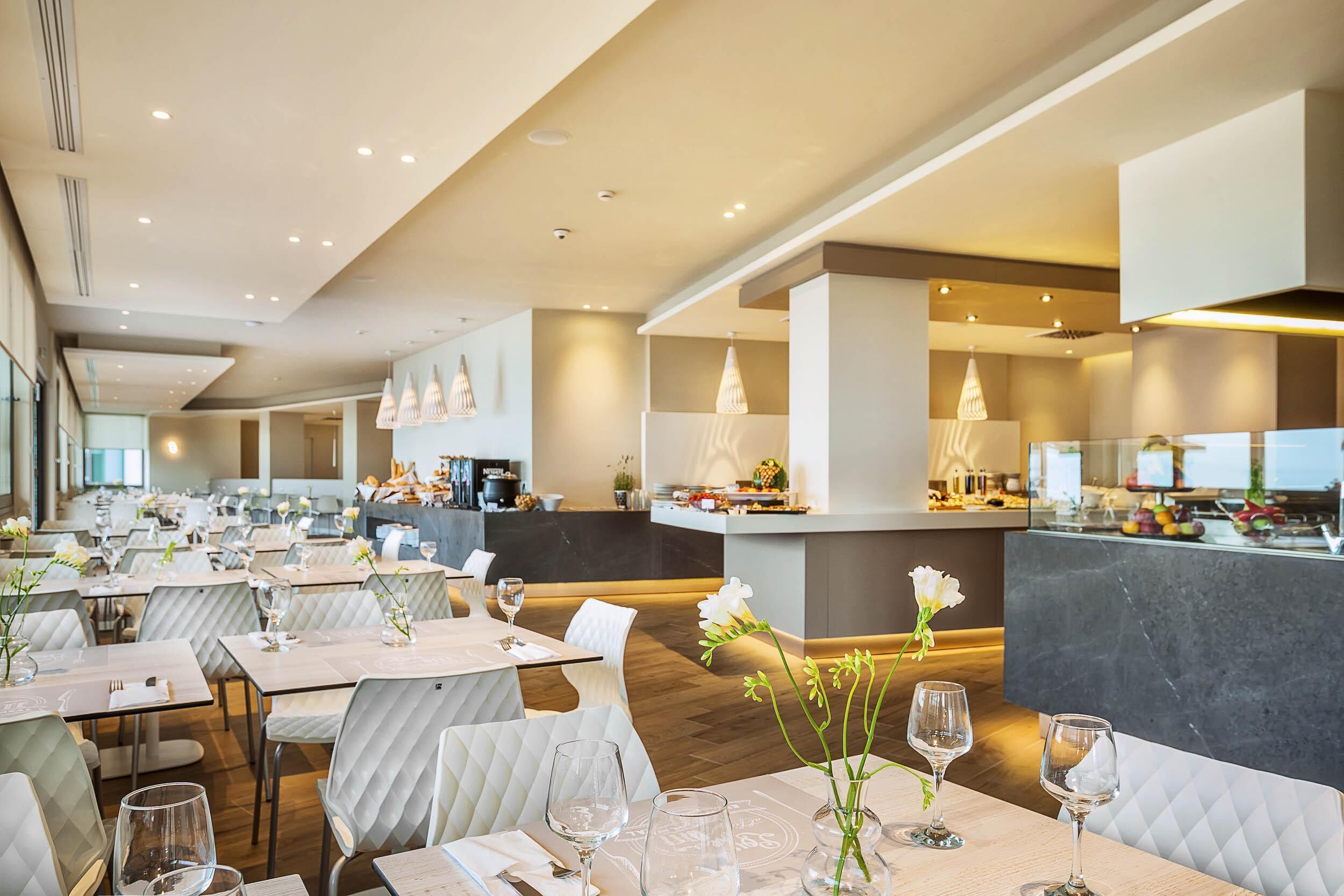 Un restaurante espacioso con varias mesas, sillas y una zona de bar central.