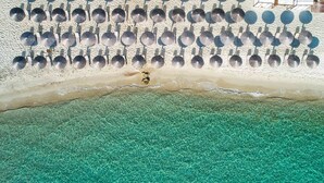 Une plage bordée d’une rangée de parasols et dotée d’un rivage sablonneux.