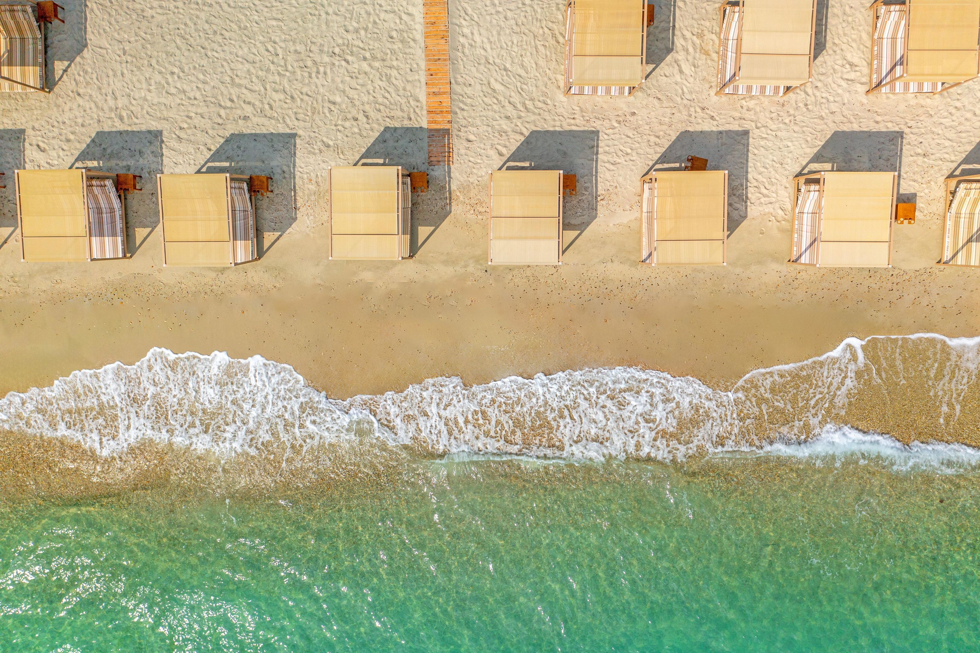 A beachside hotel with rows of sunbeds and a sandy beach.
