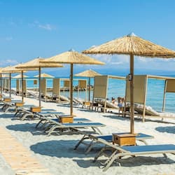 Na praia, espreguiçadeiras, guarda-sóis, toalhas de praia