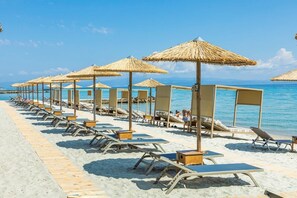 En la playa, sillas reclinables de playa, sombrillas, toallas de playa