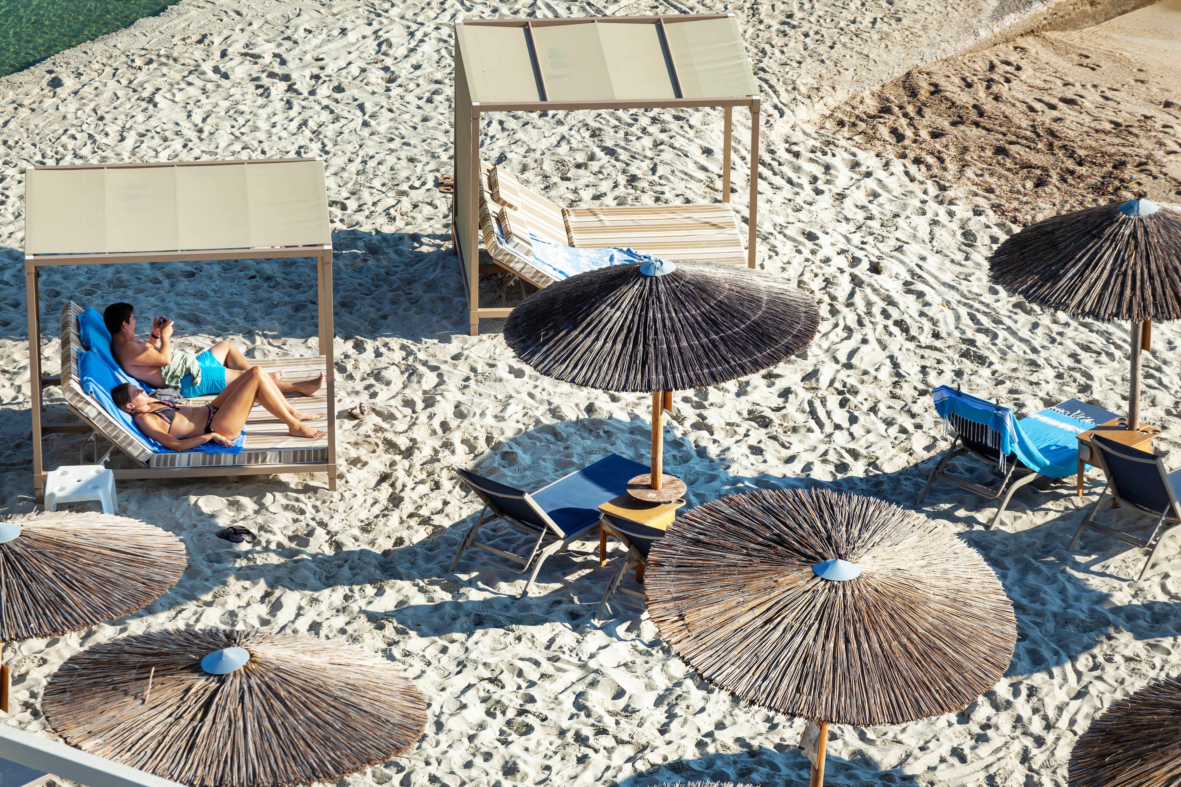 A beach with lounge chairs, umbrellas, and a wooden structure.