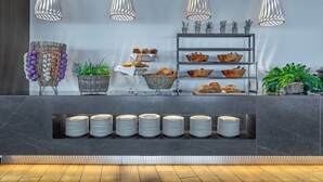 A modern reception area with a marble counter, baskets of bread, and potted plants. - Ammon Zeus Luxury Beach Hotel (Kassandra)