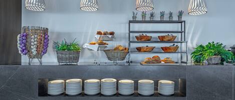 Un espace d’accueil moderne avec un comptoir en marbre, des paniers de pain et des plantes en pot.