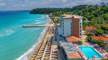 Un hotel costero con playa, piscina y vistas al mar.