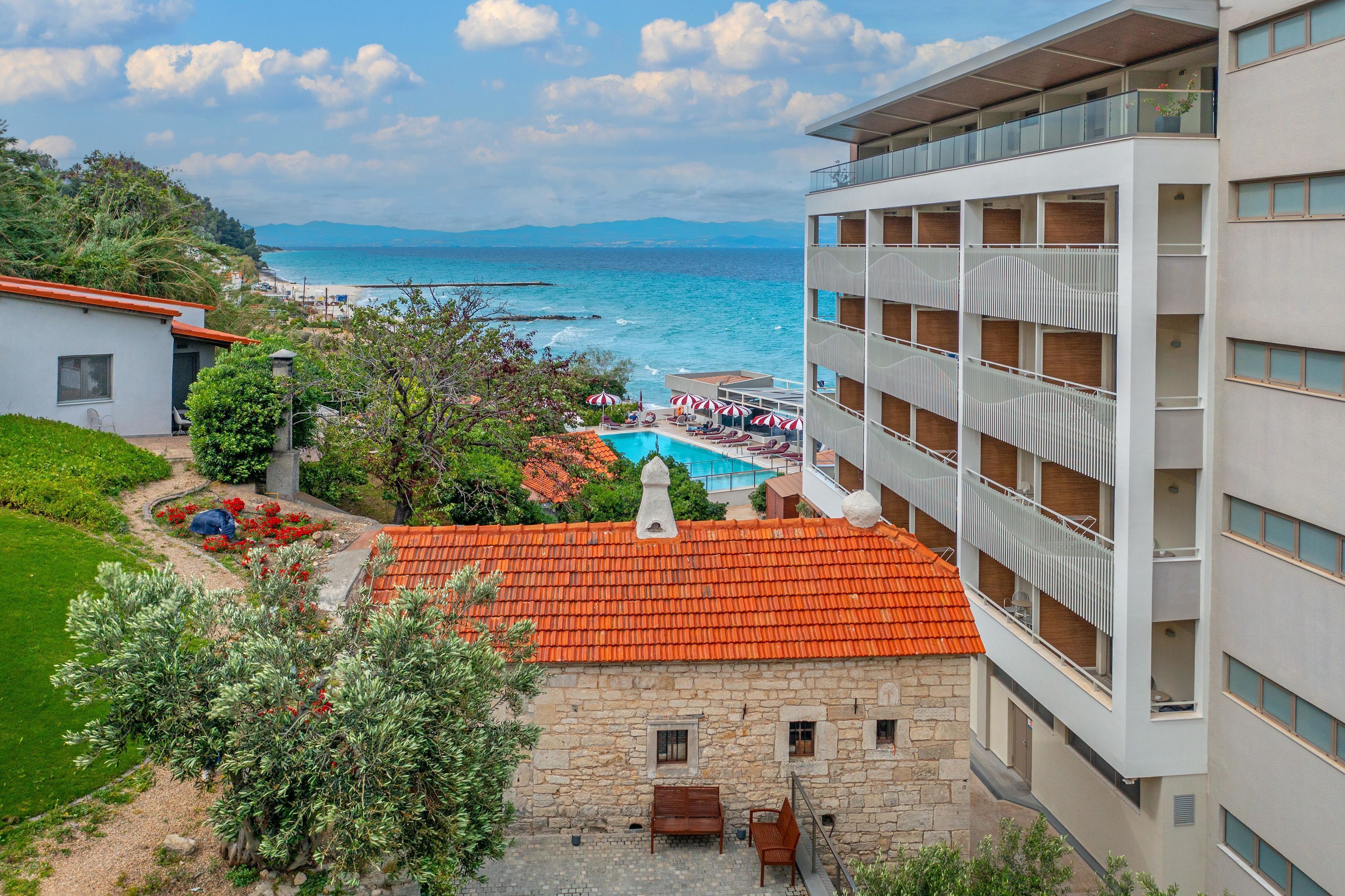 Un hotel con piscina, area salotto esterna e vista sul mare.