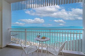 A balcony with a table and chairs, overlooking a beach with turquoise waters and a clear sky. - Ammon Zeus Luxury Beach Hotel (Kassandra)